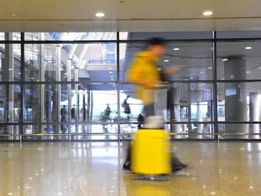Blurred person with yellow suitcase walking through airport.