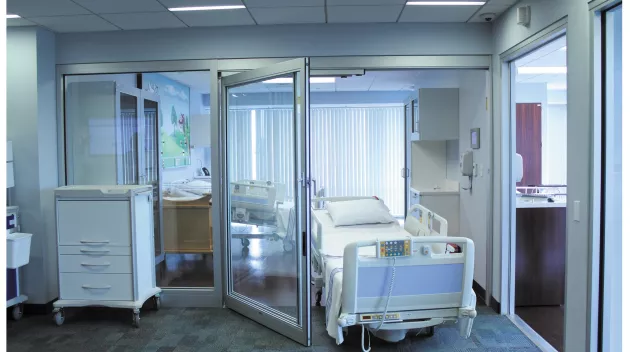 A hospital bed wheeling out of a set of doors.