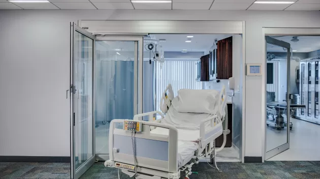 A door to a hospital room with a bed in the doorway.