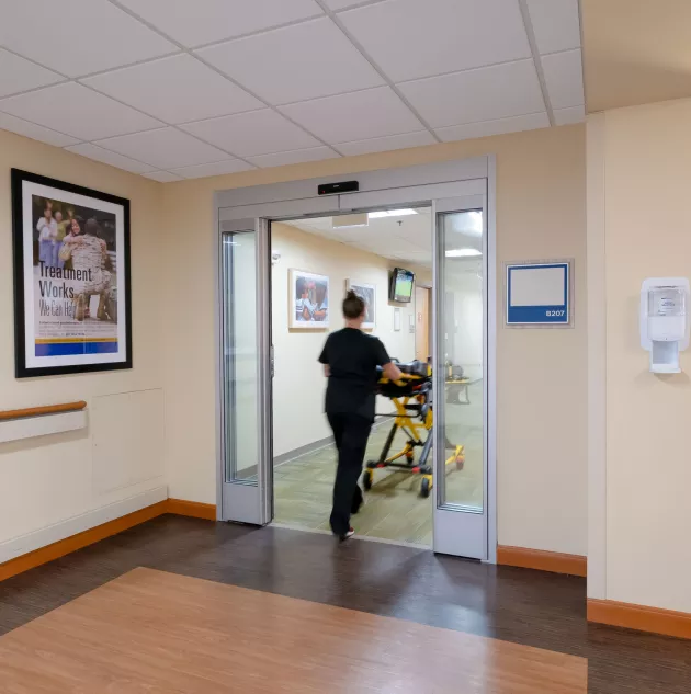 Stanley Durafit Ann Arbor-257.jpg A healthcare worker wheeling a gurney through a set of doors.