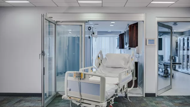 A door to a hospital room with a bed in the doorway.