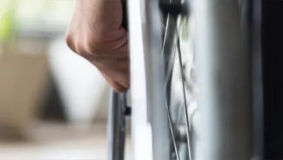 Close up of hand pushing wheelchair wheel.