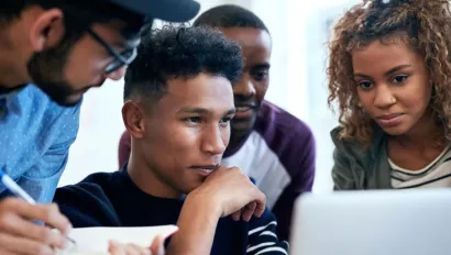 Students gather around computer screen.