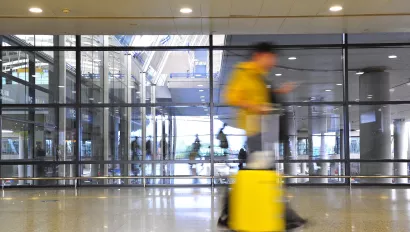 Blurred person with yellow suitcase walking through airport.